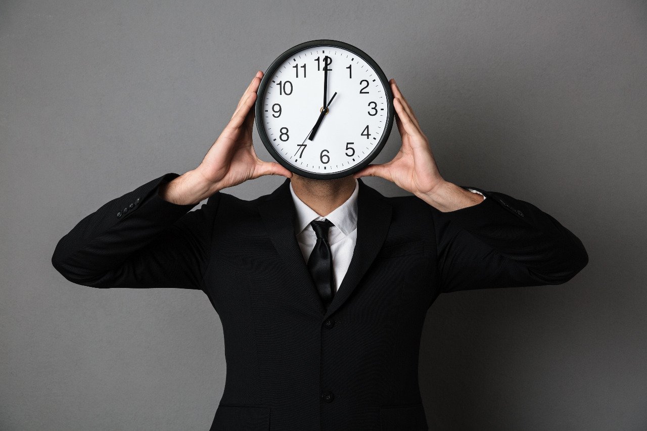 person-holding-analogue-wall-clock-in-front-of-face