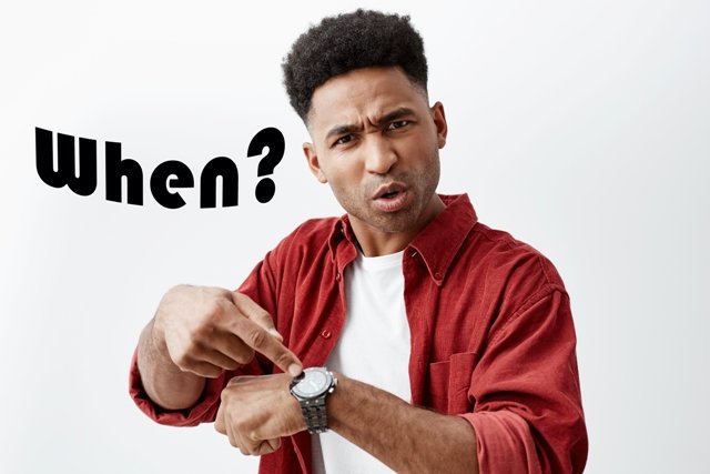 dark-skinned-man-with-dark-curly-hair-white-t-shirt-red-shirt-pointing-hand-watch-with-angry-face-expression-asking-when